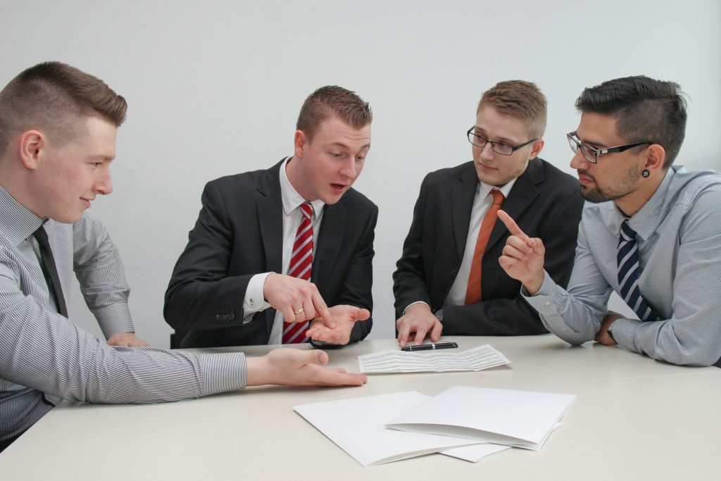 Business meeting with four men debating.